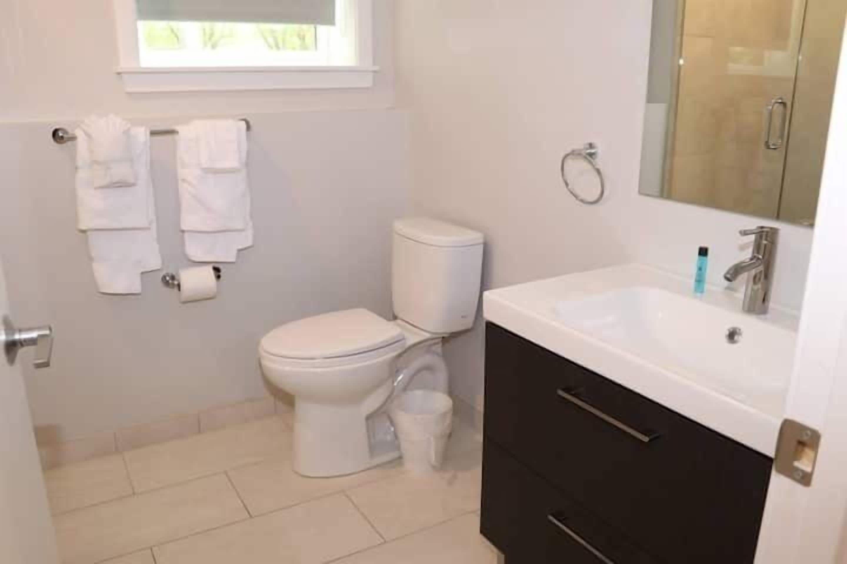 Et badeværelse med toilet, vask og spejl.