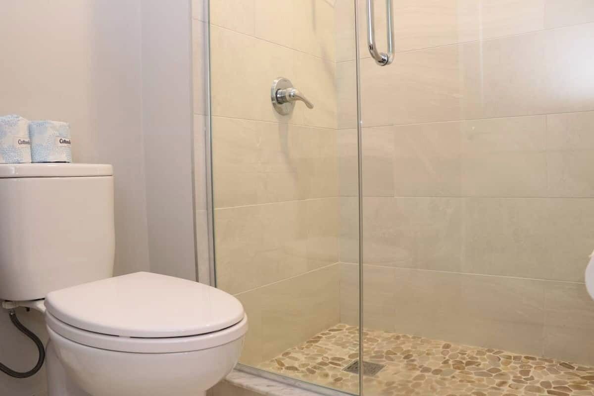 A bathroom with a toilet, a shower with a glass door, and a tiled floor.