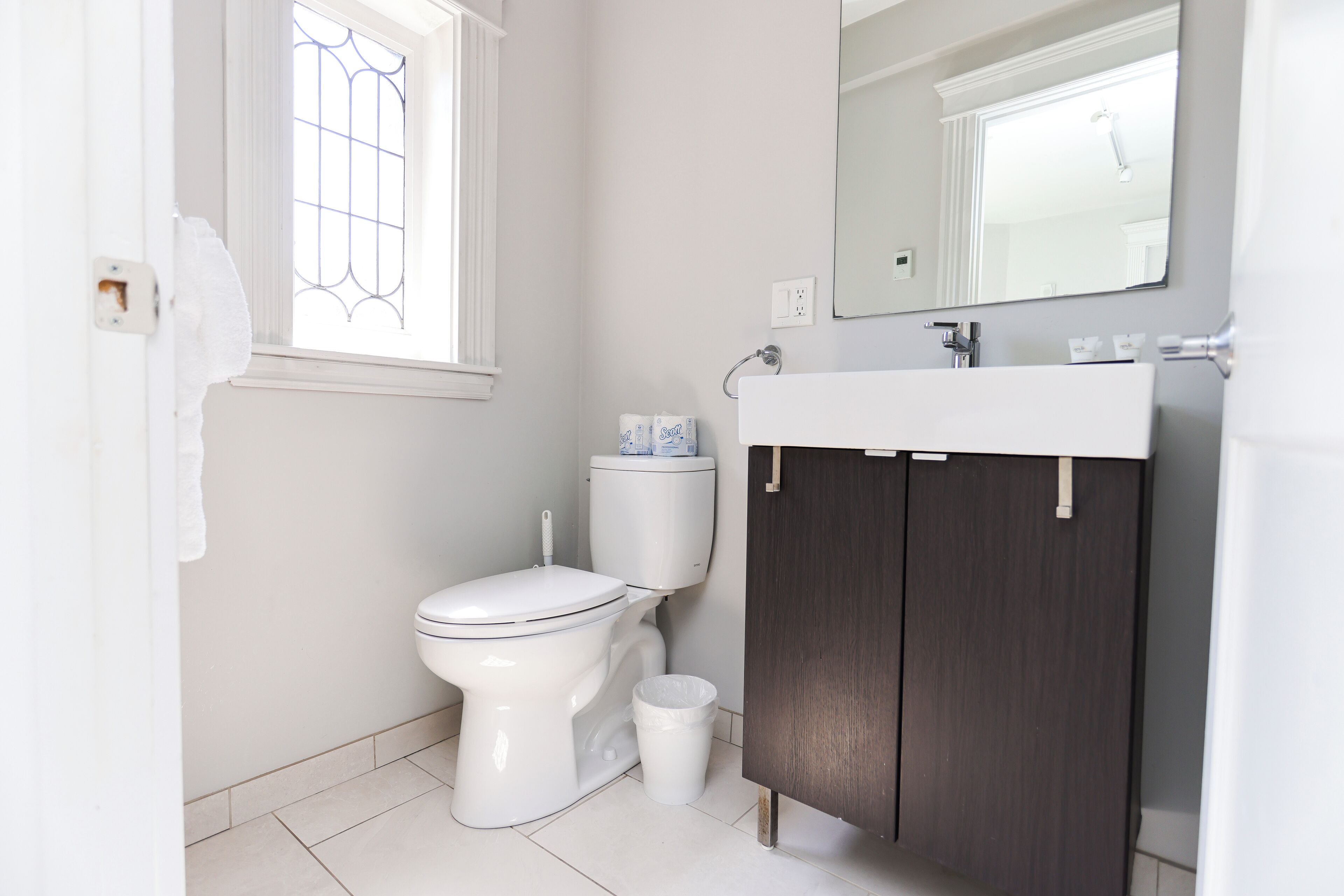 Ein Badezimmer mit Toilette, Waschbecken, Spiegel und Fenster.