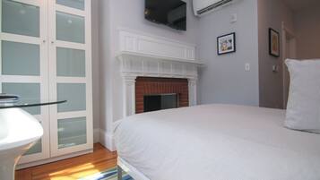 A bedroom with a bed, a fireplace, a TV mounted on the wall, and a door with frosted glass panels.