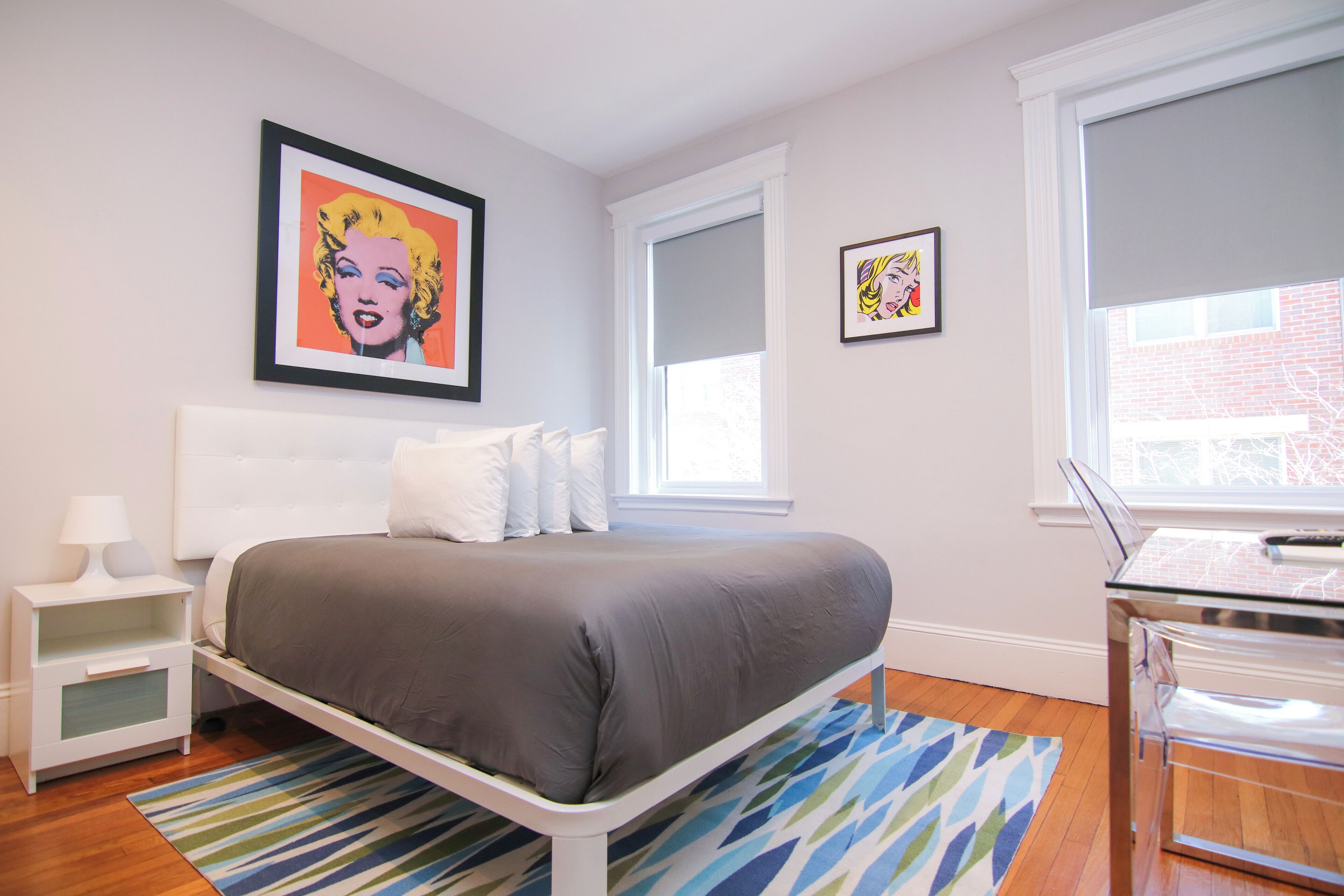Une chambre à coucher avec un lit, des tables de chevet, un bureau et une fenêtre.