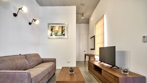 A modern living room with a sofa, coffee table, TV, and artwork on the wall. - Vallettastay Harbor Gem 2 bedroom  (Valletta)