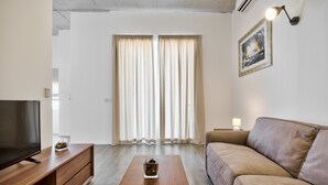 A modern living room with a flat-screen TV, wooden coffee table, beige sofa, and a framed picture on the wall. - Vallettastay Harbor Gem 2 bedroom  (Valletta)