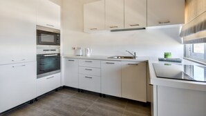 A modern kitchen with white cabinets, a built-in oven, a microwave, and a stainless steel sink. - Vallettastay Harbor Gem 2 bedroom  (Valletta)