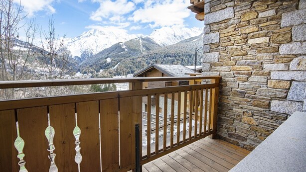 A wooden balcony with a stone wall, overlooking a snowy mountain landscape. - InstaView - One Bedroom Apartment, Sleeps 4 (Pontagna)