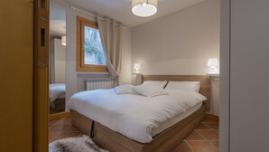 A bedroom with a wooden bed, two bedside lamps, a window with curtains, and a radiator. - InstaView - One Bedroom Apartment, Sleeps 4 (Pontagna)