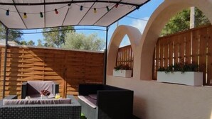 An outdoor patio area with a covered seating area, artificial grass, and a wooden fence. - Nice villa with pool in Las Tres Calas near the beach! (Les Tres Cales)