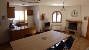 A kitchen with wooden cabinets, a dining table, chairs, a television, and a fireplace. - Nice villa with pool in Las Tres Calas near the beach! (Les Tres Cales)