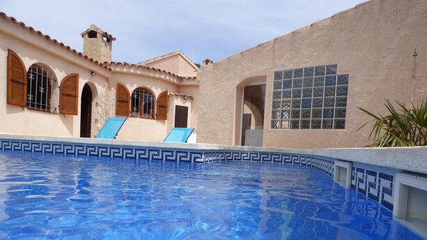 A swimming pool with blue tiles, a building with arched windows, and a tiled wall. - Nice villa with pool in Las Tres Calas near the beach! (Les Tres Cales)