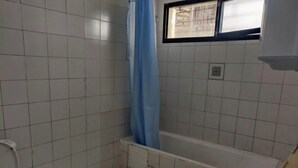 Een kleine badkamer met toilet, bad en wastafel.
