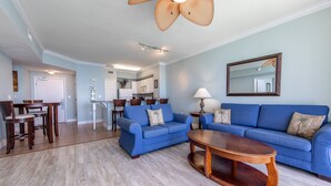 A spacious living room with a blue sofa, a wooden coffee table, and a ceiling fan.