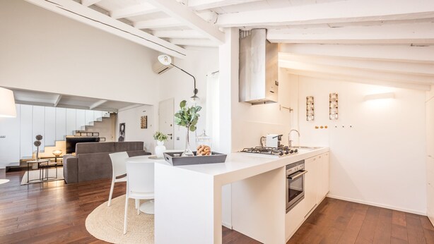 A modern kitchen with a central island, white cabinetry, and a built-in oven. - Emilia Suite Urban (Modena)