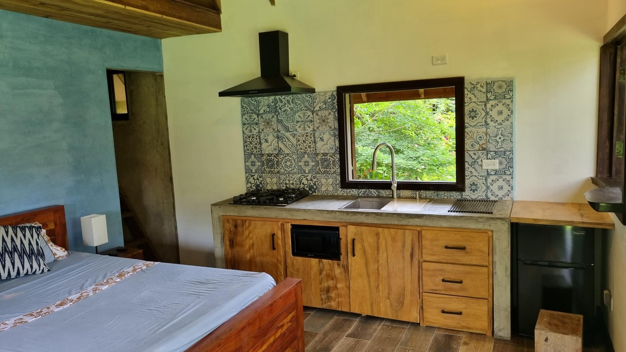 A compact kitchen with a window, wooden cabinets, a built-in stove, and a sink.