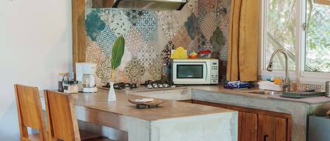 A kitchen with a microwave, stove, and wooden chairs.