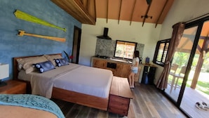 A bedroom with a bed, wooden desk, and a window with a view of greenery. - Cabañas Naturaleza (Bocas del Toro)
