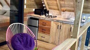 Ein rustikales Holzhaus-Interieur mit Küchenbereich, einem Esstischstuhl und einem kleinen Tisch mit Blumen.