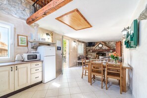 A spacious kitchen with a stone fireplace, wooden beams, and a dining area with a table and chairs.
