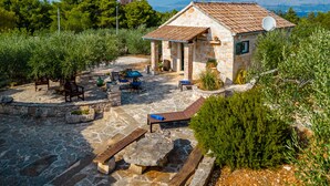 Une maison en pierre avec un toit en tuiles, un espace extérieur aménagé pour s’asseoir et une vue sur le paysage.