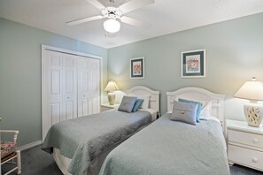 A bedroom with two beds, a ceiling fan, and two bedside lamps.