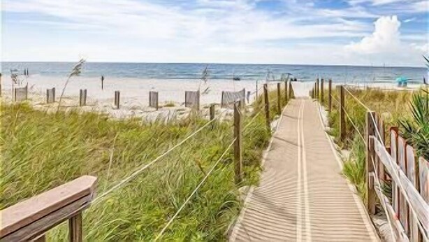 Une promenade en bois qui mène à une plage, avec un ciel dégagé.
