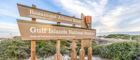 Un letrero de madera que indica 'Rosamond Johnson Beach' y 'Parque Nacional Islas del Golfo'.