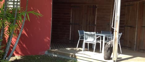 Ein überdachter Außenbereich mit Tisch und Stühlen, einem Holzzaun und einer roten Wand.