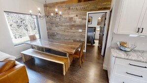 A modern kitchen with white cabinets, a marble countertop, and a wooden dining table with benches.