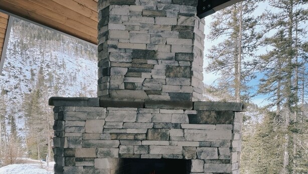 A stone fireplace with a fire burning inside, surrounded by a stone structure.