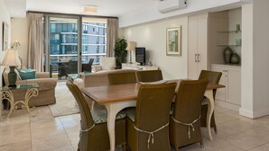 A modern living room with a dining area, large windows, and a view of the city.