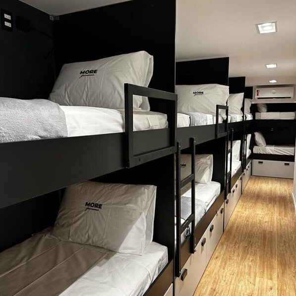 Habitación con literas, ropa de cama blanca y cabeceros negros.