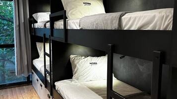 A bunk bed room with a window, a black wall, and a wooden floor.