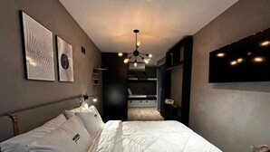 A bedroom with a bed, a ceiling light, and a wall-mounted TV. - More Ipanema (Rio de Janeiro)