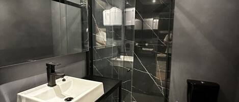 Ein modernes Badezimmer mit Duschkabine aus Glas, Waschbecken in Weiß und Toilette in Schwarz.