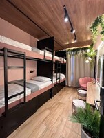 Una habitación compacta con literas, un pequeño espacio de descanso y un espejo.