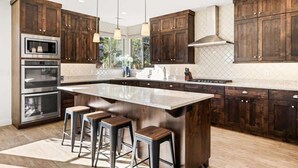 Una cucina moderna con mobili in legno scuro, elettrodomestici in acciaio inossidabile e una grande isola con sgabelli da bar.