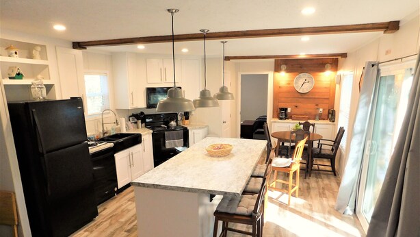 Una cocina moderna con una isla central, suelo de madera e iluminación colgante.