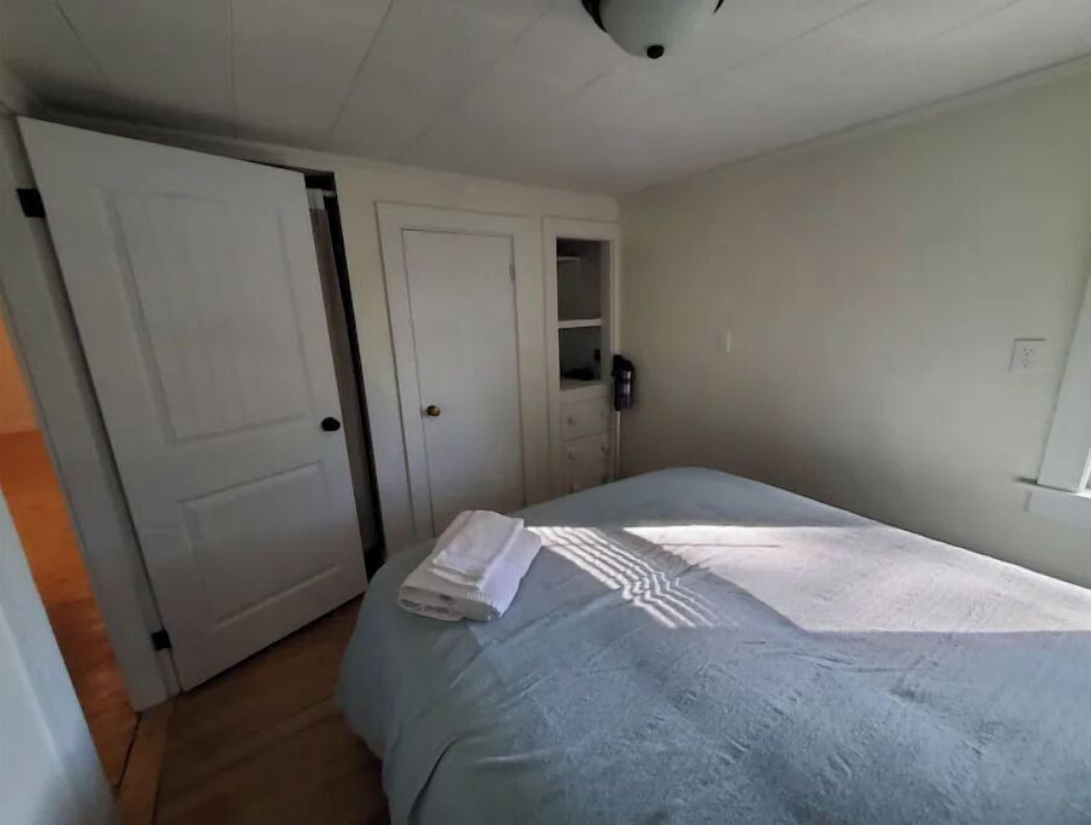 Un dormitorio con una cama, un armario y una pequeña estantería.