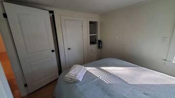 Un dormitorio con una cama, un armario y una pequeña estantería.