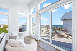 A spacious living room with a large sliding glass door leading to an outdoor patio with a view of the sea. - Best of the Best! Pet Friendly, 400 Feet to Beach. Pool, LSV, Elevator, Bikes (Santa Rosa Beach)