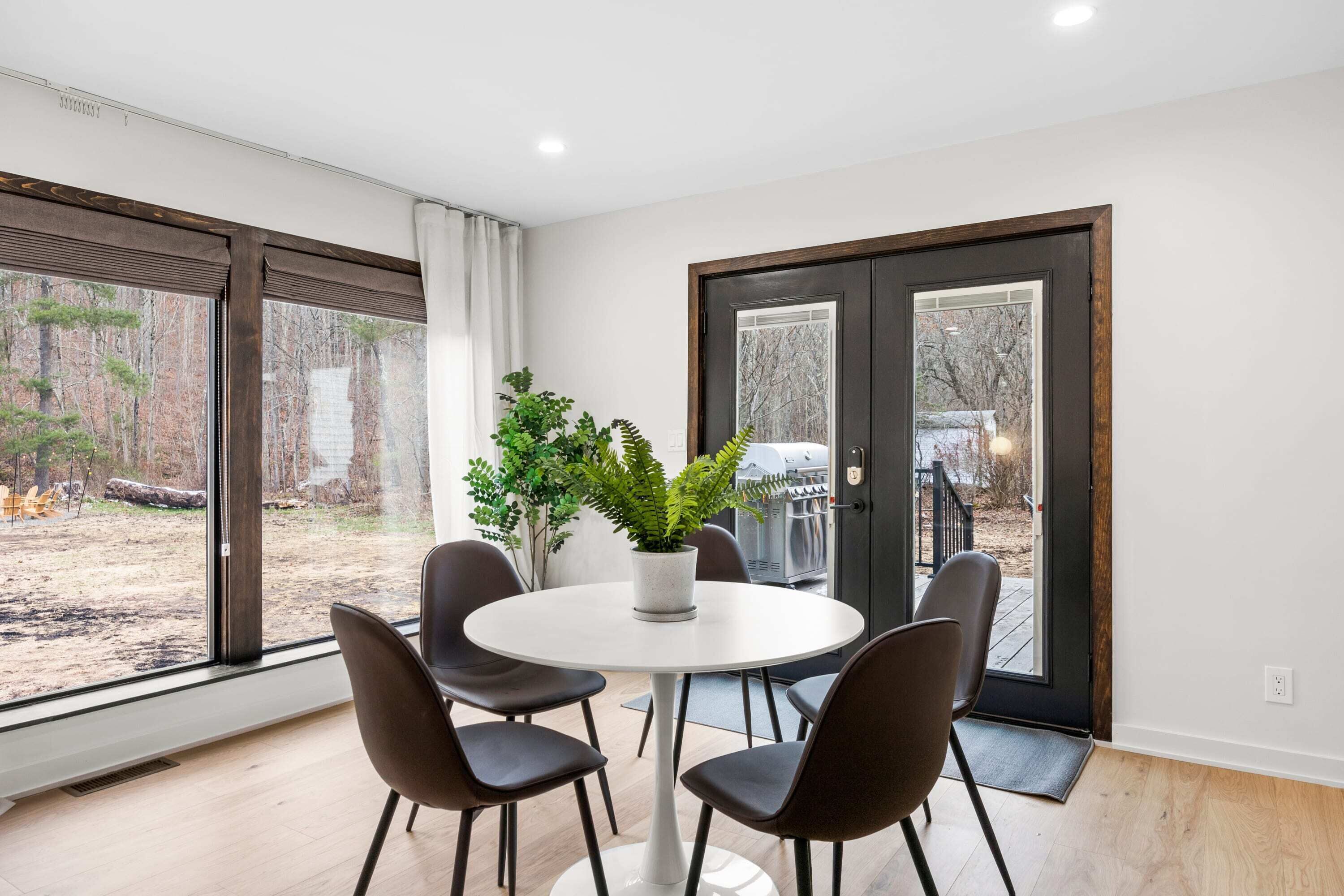 A modern dining area with a round table, four chairs, and a potted plant.