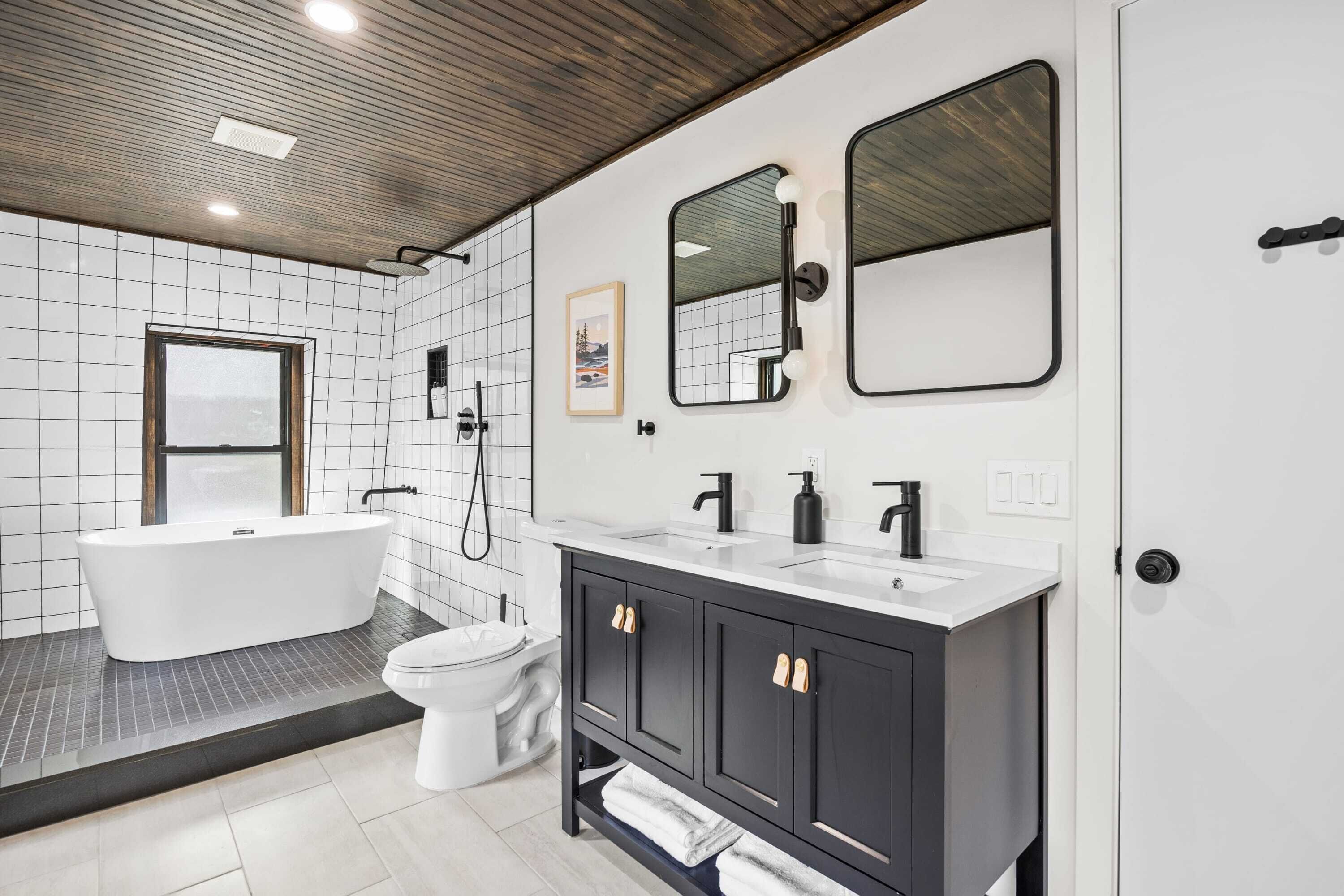 A modern bathroom with a freestanding bathtub, a toilet, and a vanity with a mirror.