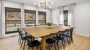 Un vaste espace dédié à la salle à manger, avec une grande table en bois, des chaises noires et un lustre moderne.