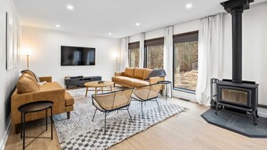 Un salon moderne avec un canapé, des fauteuils, un téléviseur et une cheminée.