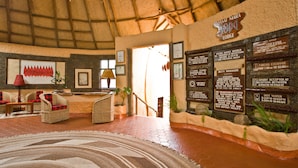 A reception area with wicker furniture, a large rug, and informational signs about lodge policies.