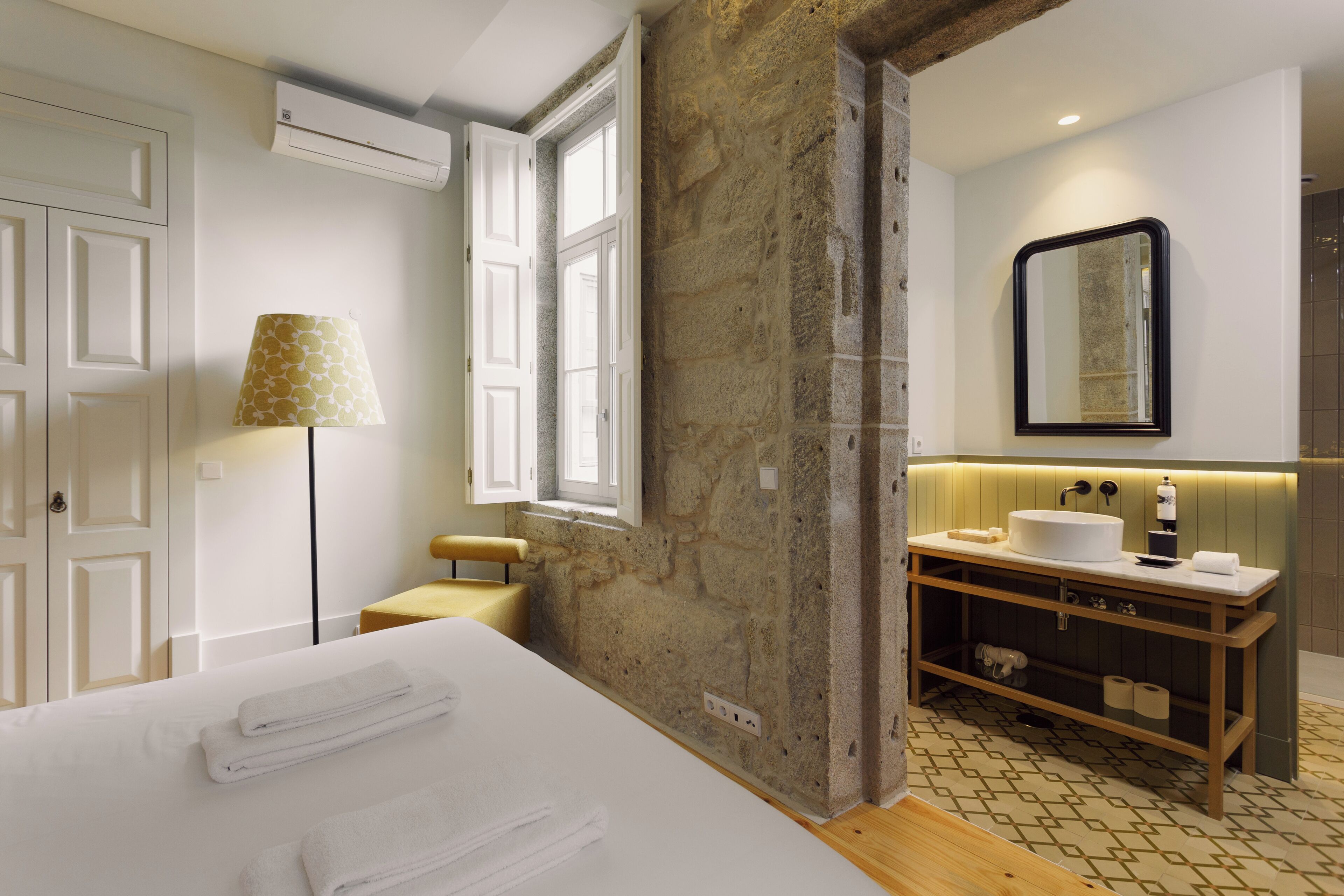 Une chambre d’hôtel moderne dotée d’un grand lit, d’une coiffeuse en bois avec un lavabo, d’un miroir et d’une fenêtre offrant une vue agréable.