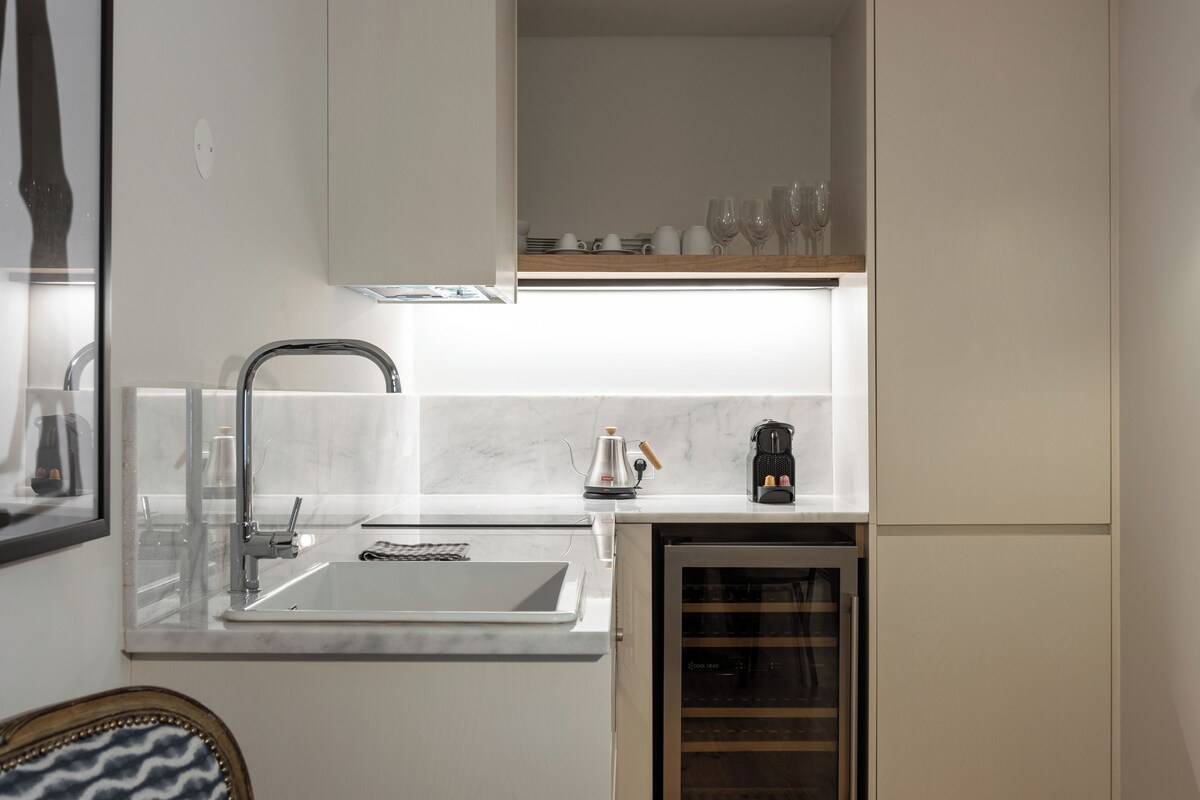 Uma cozinha moderna com pia embutida, um refrigerador de vinhos e uma máquina de café.