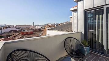 Terraço no telhado com vista para a paisagem urbana, um edifício moderno com amplas janelas e um vaso de planta.