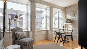 A modern room with large windows, a sofa, a small round table, and a television. - Líbere Porto Laranjais (Porto)