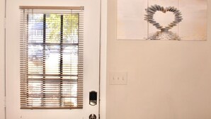 A door with a window, a wall-mounted light switch, and a framed artwork of a heart made of stones. - Cheerful 2 bedroom townhouse with indoor Fireplace (Tucker)