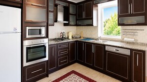 Une cuisine moderne avec des meubles en bois foncé, des appareils en acier inoxydable, une fenêtre offrant une belle vue et un dosseret carrelé.